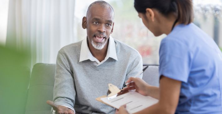 Man talking to healthcare provider who is holding a clipboard