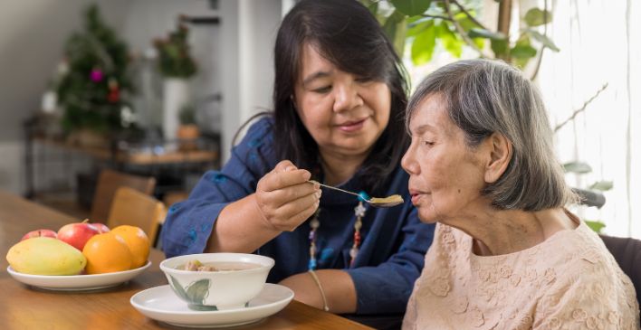Woman feeding her elderly mother soup