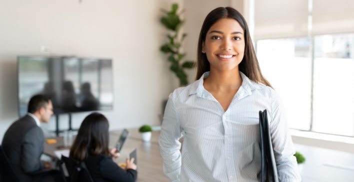 Smiling woman holding a binder in an office